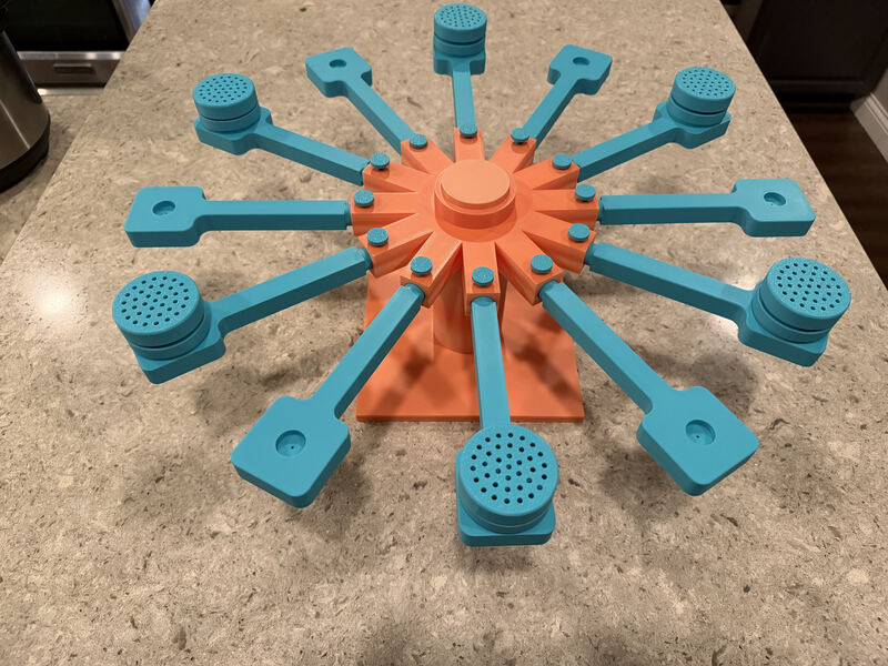 Teal and orange 3D printed scent training wheel with perforated cups on radiating arms.