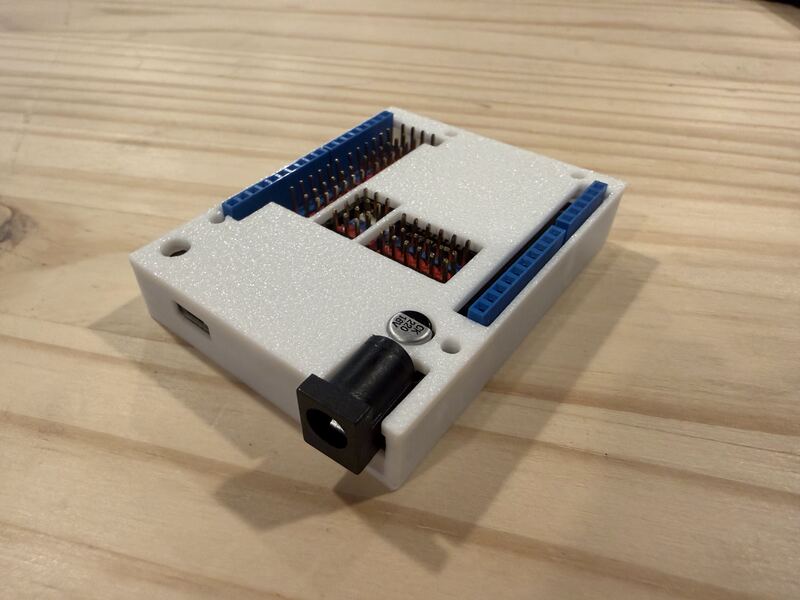 Cream colored 3D printed vented electronics enclosure housing a controller board with terminal blocks.